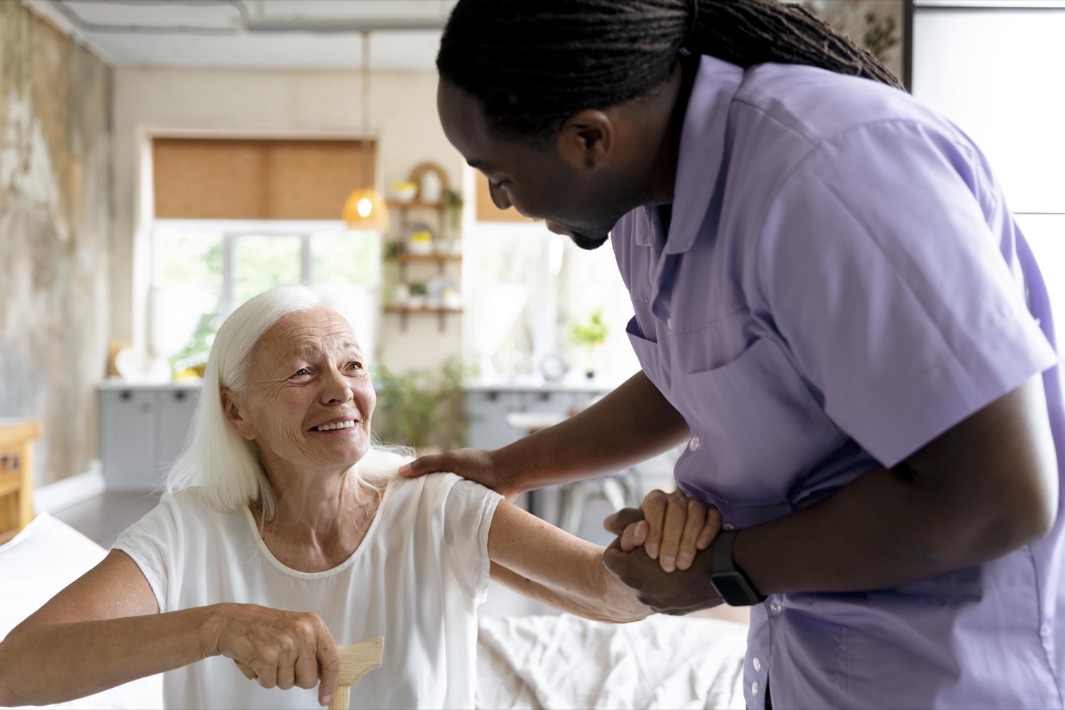 A caregiver supporting a smiling senior woman at home