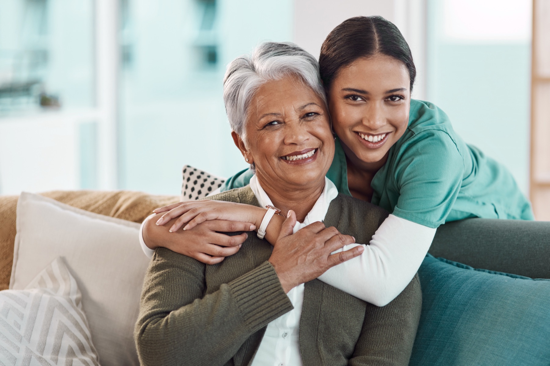 A caregiver embracing a smiling senior woman at home